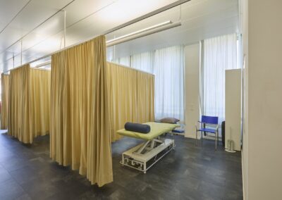 Behandlungskabine mit Liege, abgetrennt durch einen Vorhang